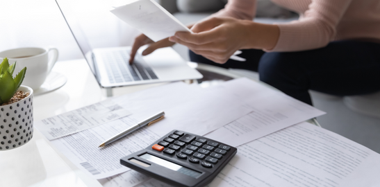 hesap makinesiyle hesap yaparak bilgisayar ekranına yazan bir el