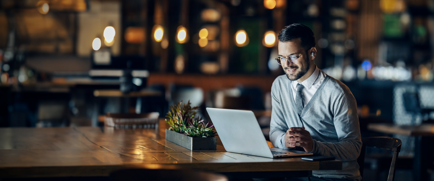 a young businessman working in front of a computer in a cafe