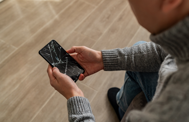 kırılmış cep telefonu ekranına bakan biri