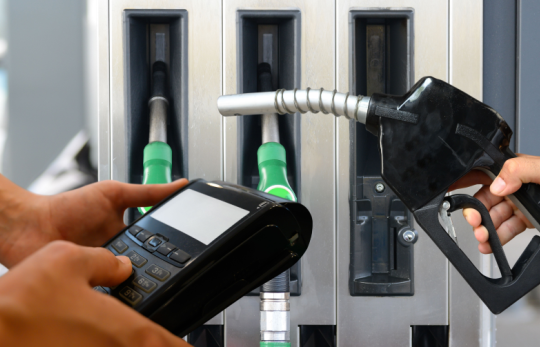 akaryakıt dolum yeri önünde pos cihazı tutan istasyon görevlisi