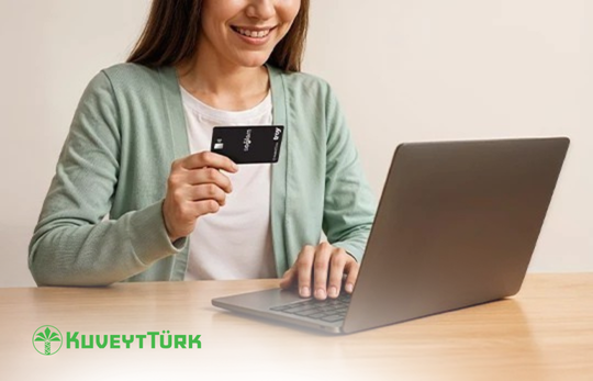 bilgisayardan işlem yaparken diğer elinde sağlam kart tutan kadın