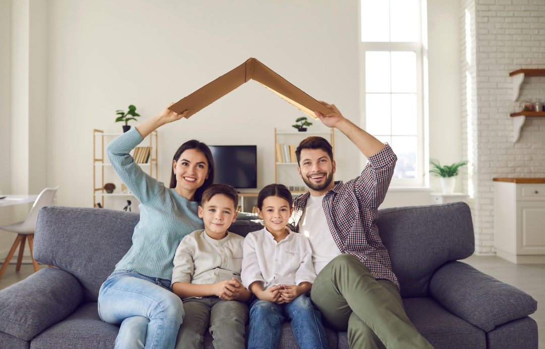 Family sitting on sofa fominga house shape with their arms