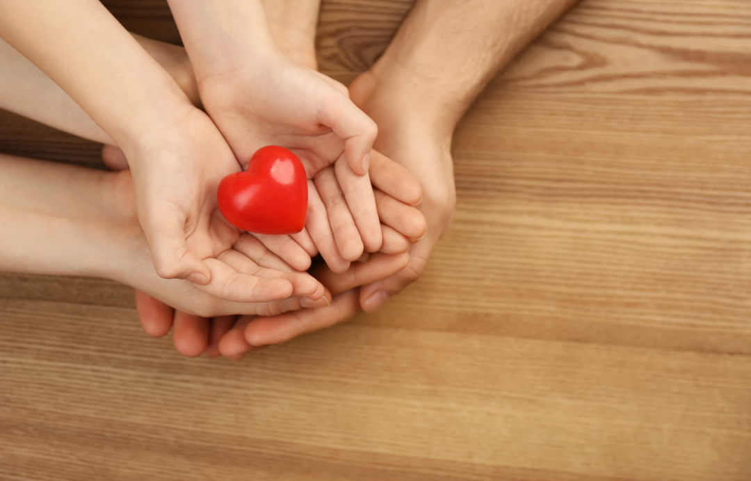  hands holding a small heart figure