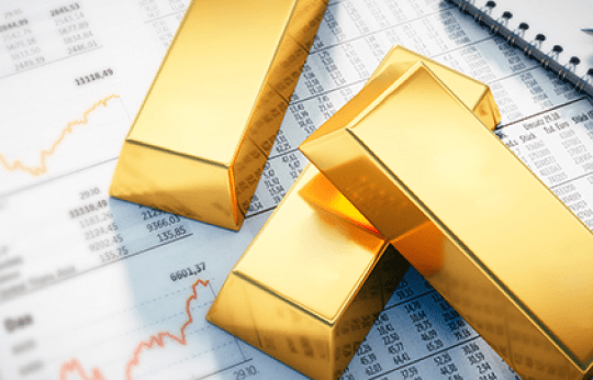 Gold bars placed on financial charts and data sheets