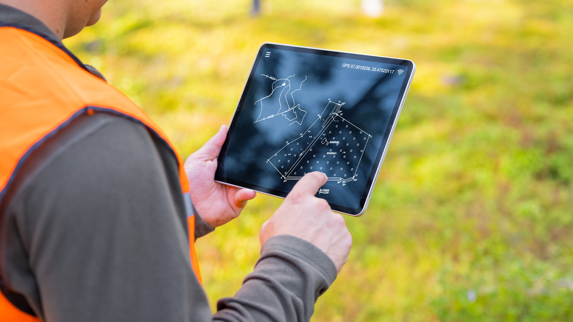A person examining a map and plans on a tablet