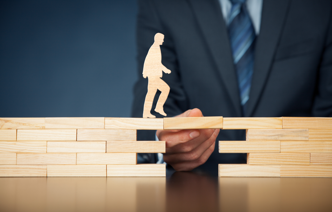 Figure crossing gap on wooden blocks with support from a hand
