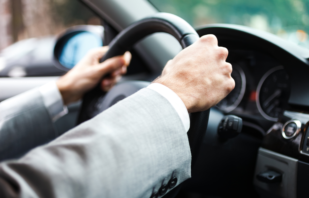 A man holding the steering wheel of the vehicle
