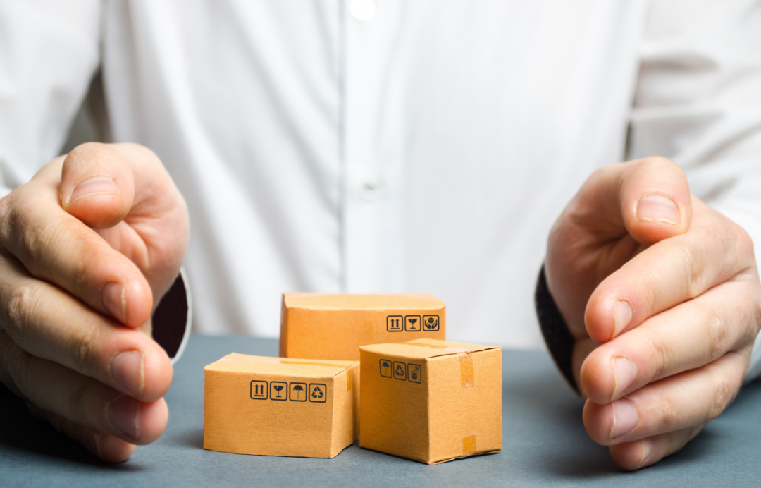 hands protecting miniature shipping boxes