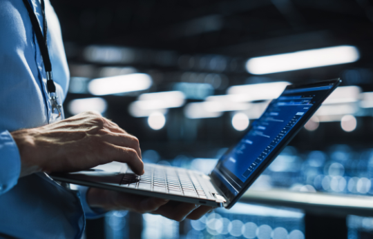 Person using laptop in a server room environment