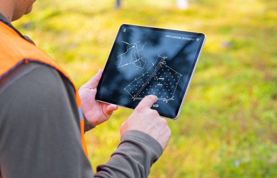 Tablet üzerinde harita ve plan inceleyen kişi
