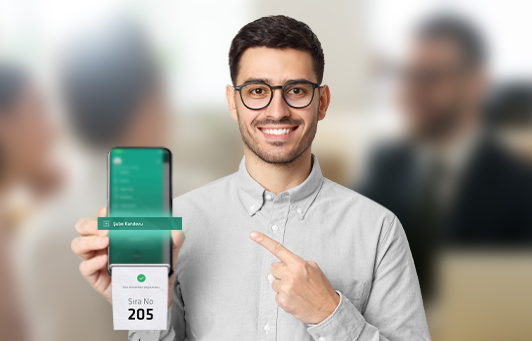 parmağı ile diğer elindeki telefonu gösteren genç adam 