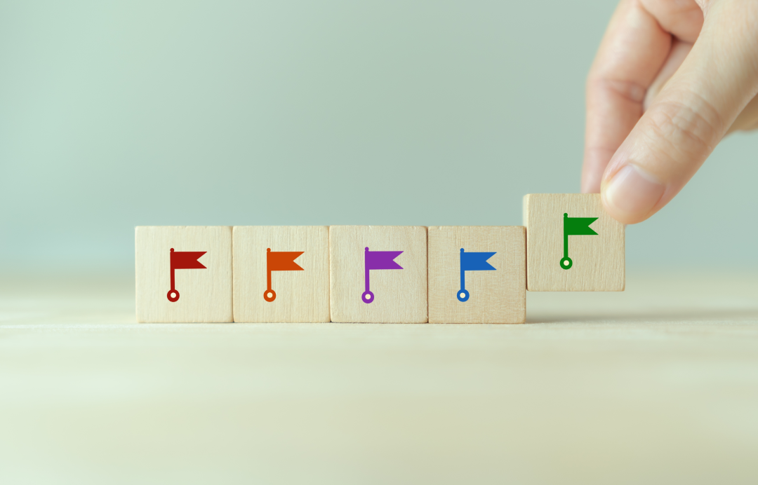 a hand arranging wooden blocks with flags on them side by side