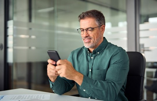 A smiling man looking at his cell phone