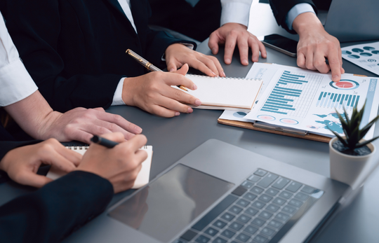 People discussing performance reports around a meeting table