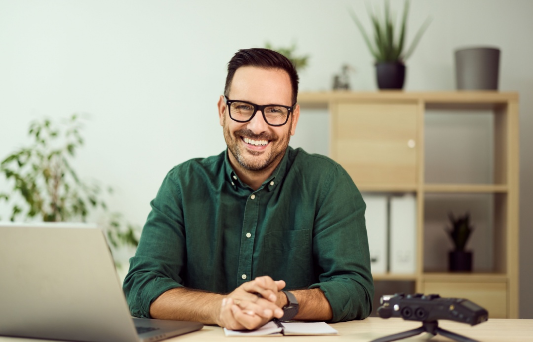 Professional smiling a desk with laptop and notebook