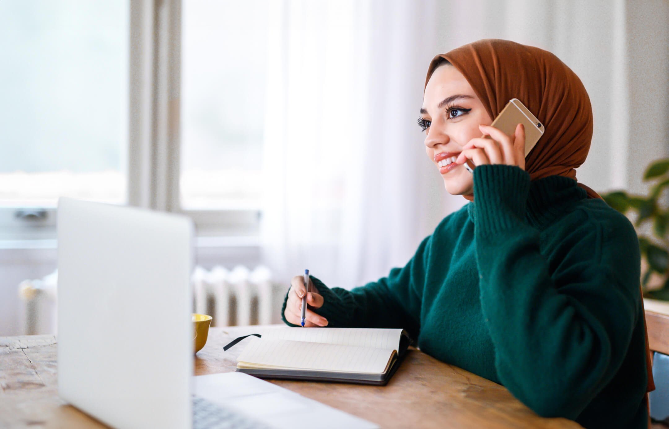 Bilgisayar başında telefonla konuşan güleryüzlü genç kadın