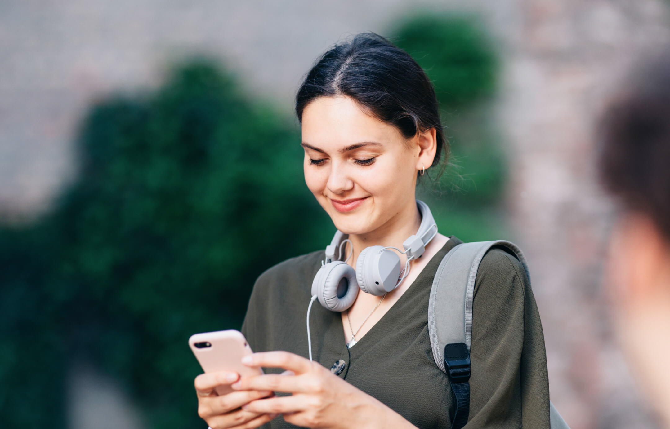 Elindeki cep telefonundan işlem yapan yeşil kıyafetli kadın