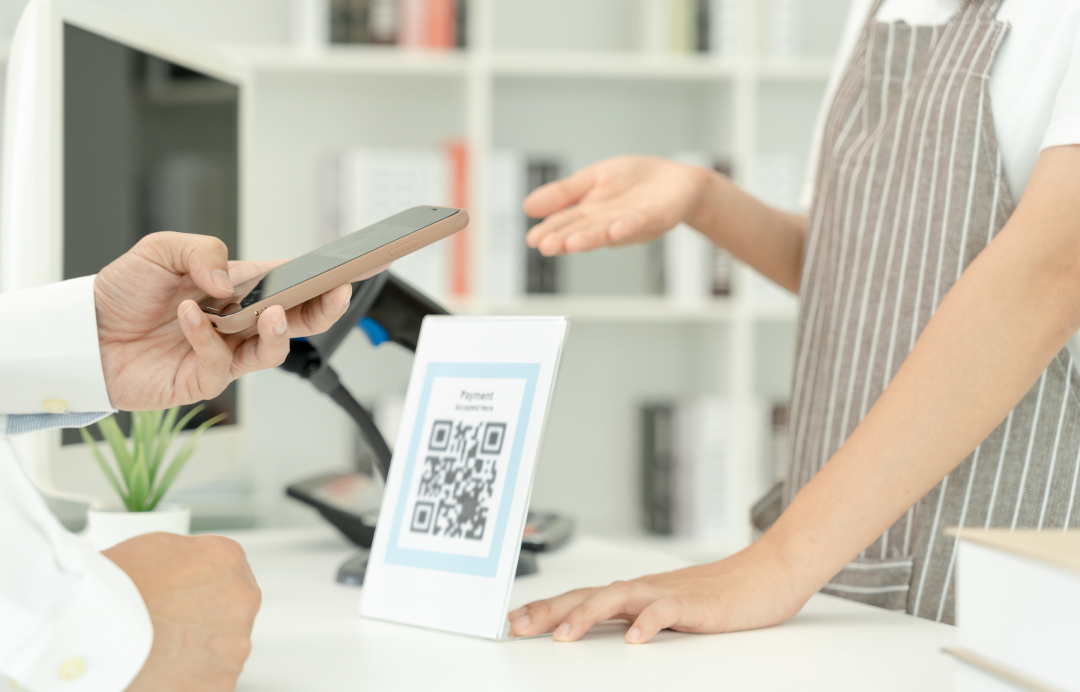 QR kodu gösteren satış danışmanı ve telefonuna bakan müşteri