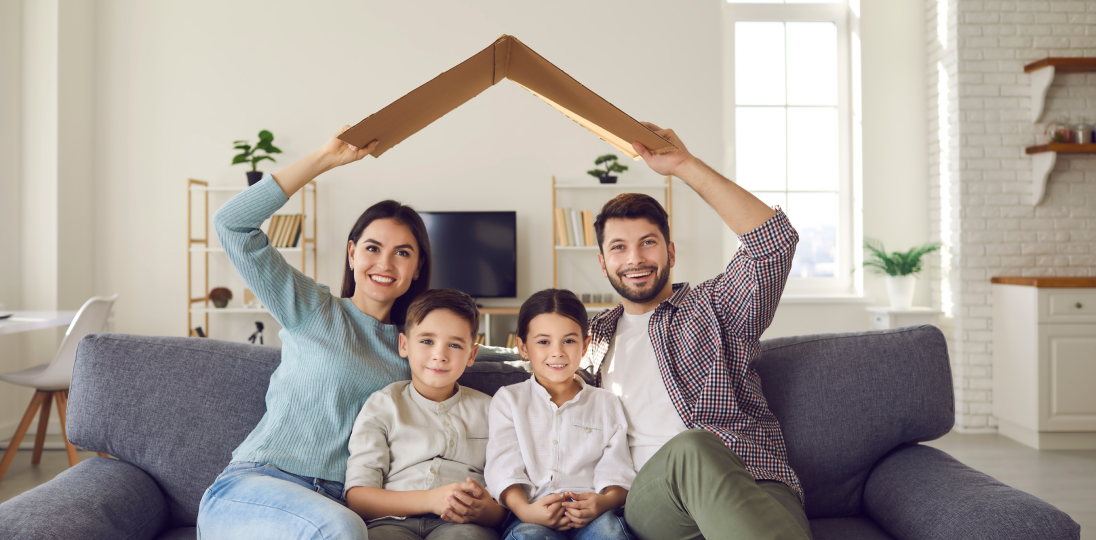 Family sitting on sofa fominga house shape with their arms