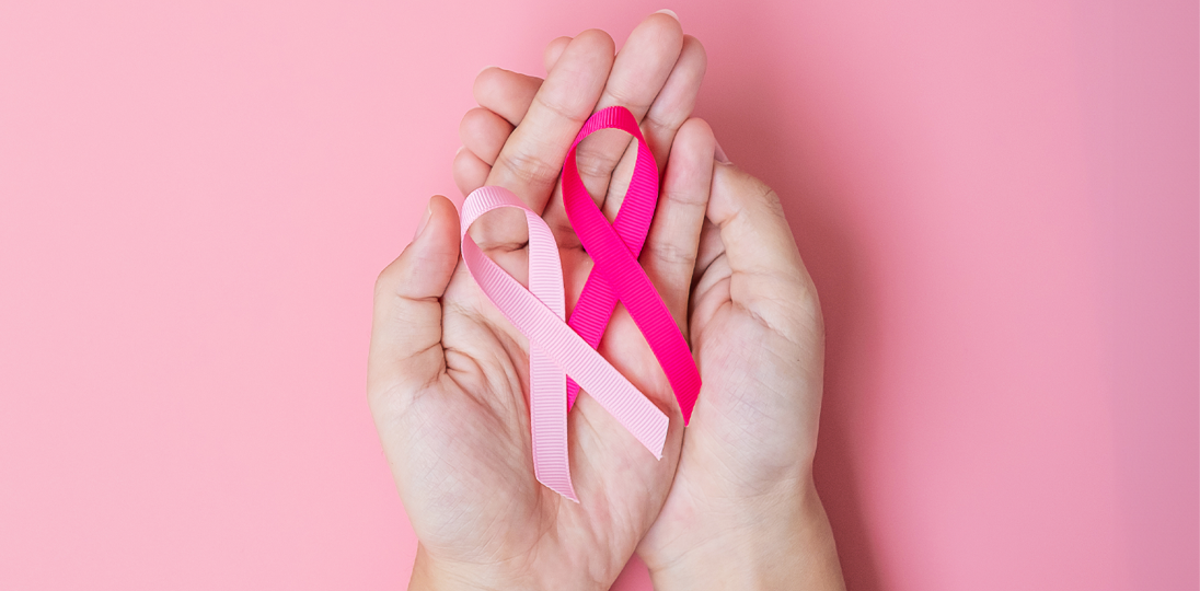 Hands holding pink and white cancer awareness ribbons