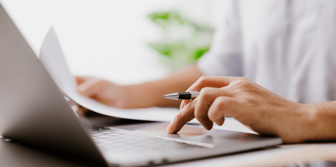 önünde laptop ve resmi belgeler bulunan kişi