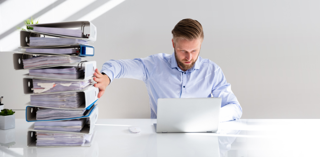 evraklarla birlikte bilgisayar ekranına bakan bir erkek müşteri