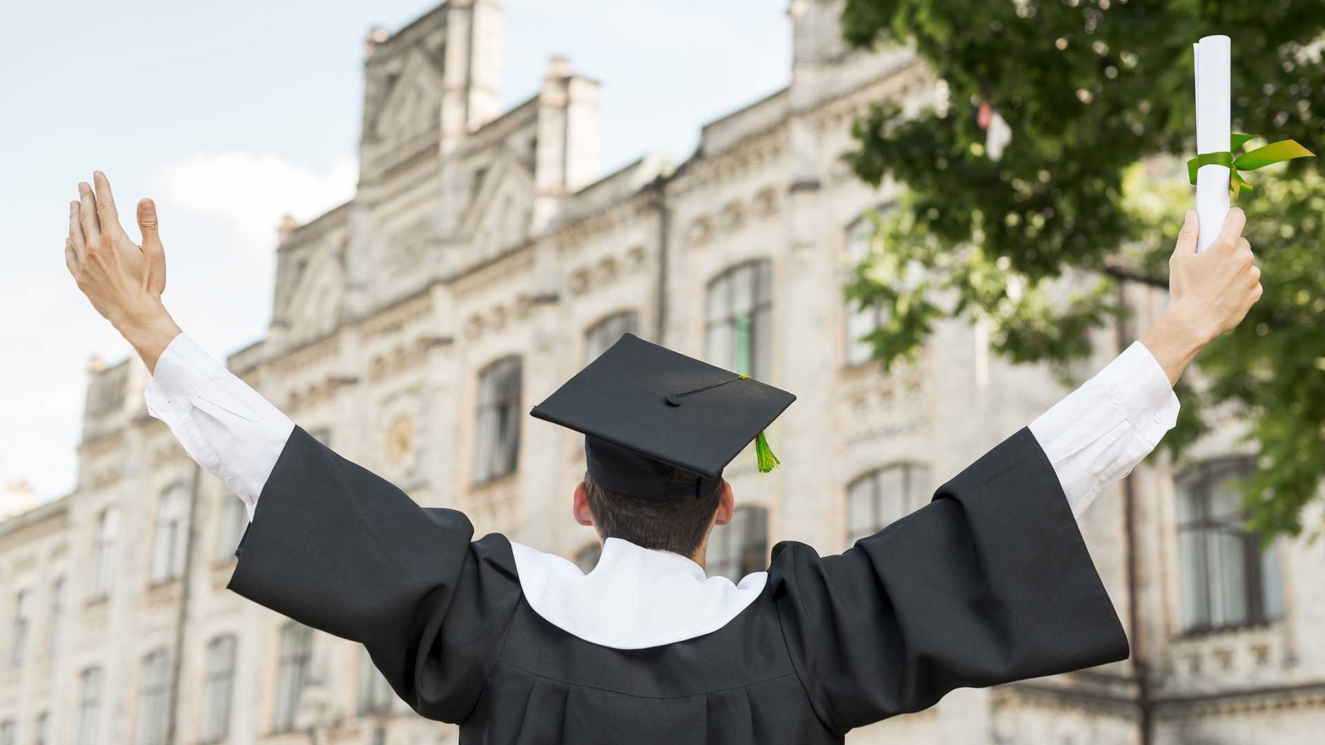 üniversite binası önünde kollarını yeni açmış kep ve cübbe giyinmiş elinde diploması olan genç