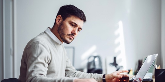 Bilgisayar başında çalışan ciddi görünümlü genç