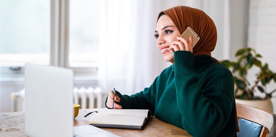 Bilgisayar başında telefonla konuşan güleryüzlü genç kadın