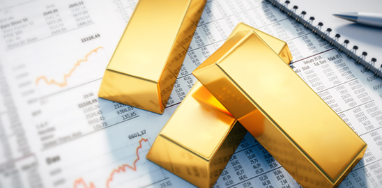 Gold bars placed on financial charts and data sheets