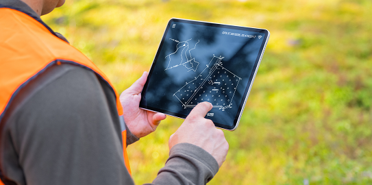 A person examining a map and plans on a tablet