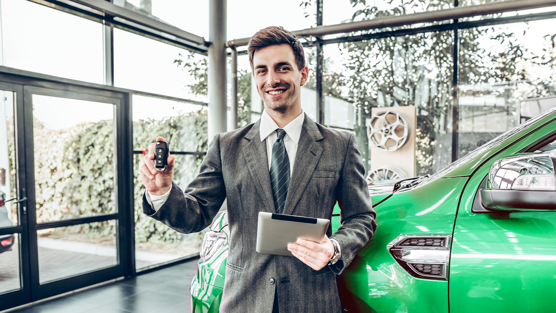 A sales consultant holding a car key and the concept of vehicle financing with a new vehicle