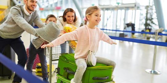 a family happily carrying their suitcases at the airport