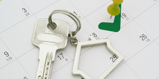 a house key with a house-shaped keychain on a white calendar page