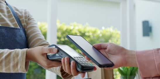 Person making contactless payment with phone at card terminal