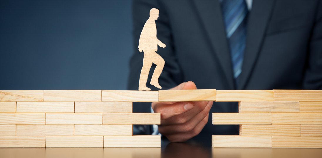 Figure crossing gap on wooden blocks with support from a hand