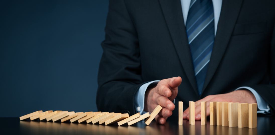 A person who stops falling dominoes with their hand thus preventing a chain reaction