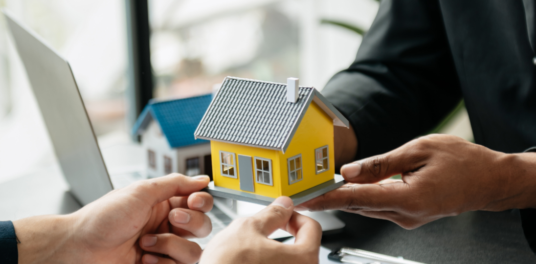 Hands exhangig a model house during a property transaction