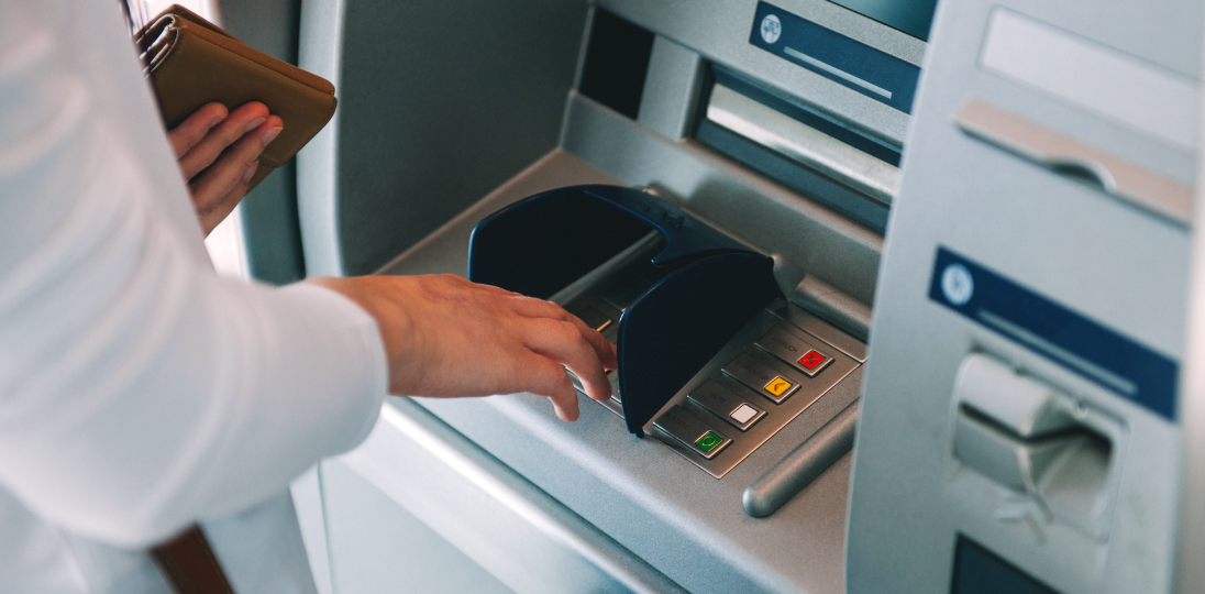 Person using ATM machine while holding a wallet