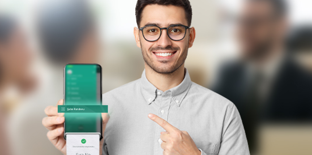 parmağı ile diğer elindeki telefonu gösteren genç adam 