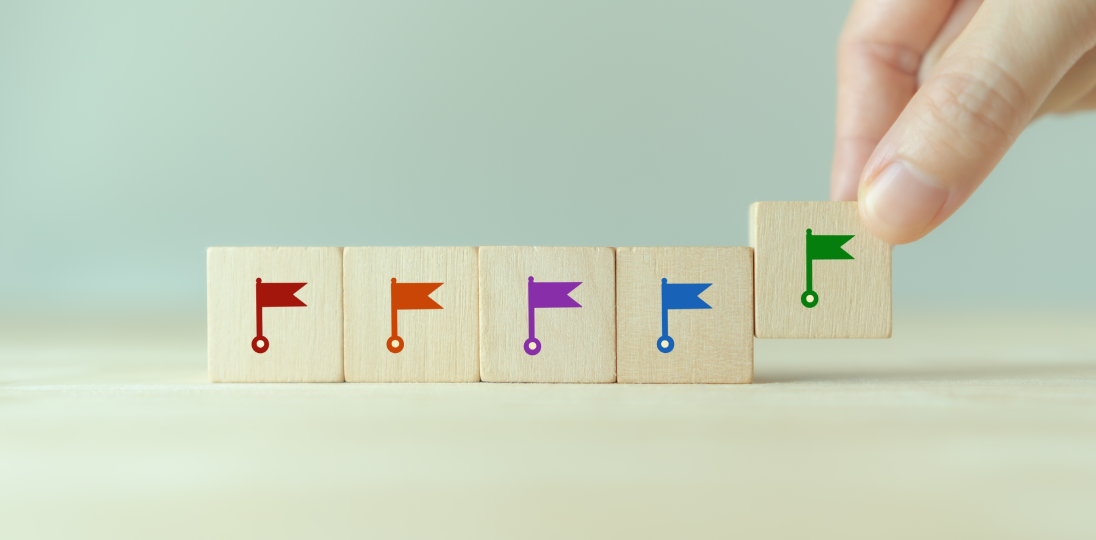 a hand arranging wooden blocks with flags on them side by side