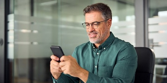 A smiling man looking at his cell phone