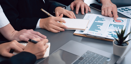 People discussing performance reports around a meeting table