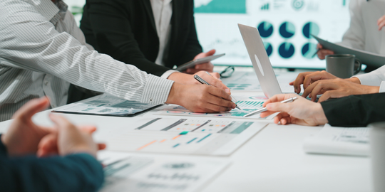 Team members discussing charts around a meeting table