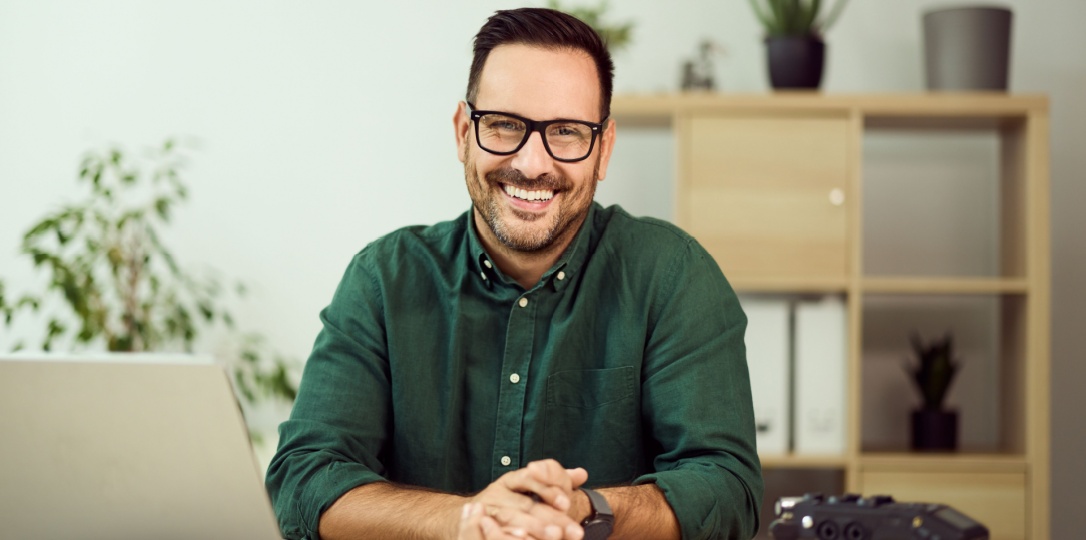 Professional smiling a desk with laptop and notebook