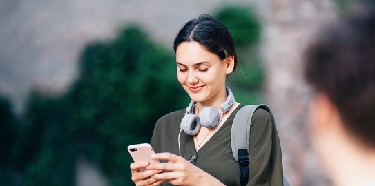 Elindeki cep telefonundan işlem yapan yeşil kıyafetli kadın