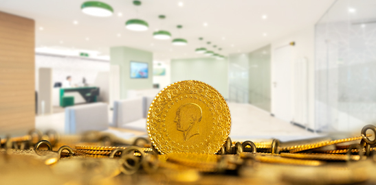 Gold coin and jewelry displayed on a surface with blurred interior background
