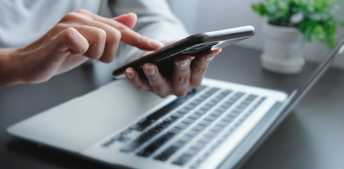 a person using their phone while working on a computer
